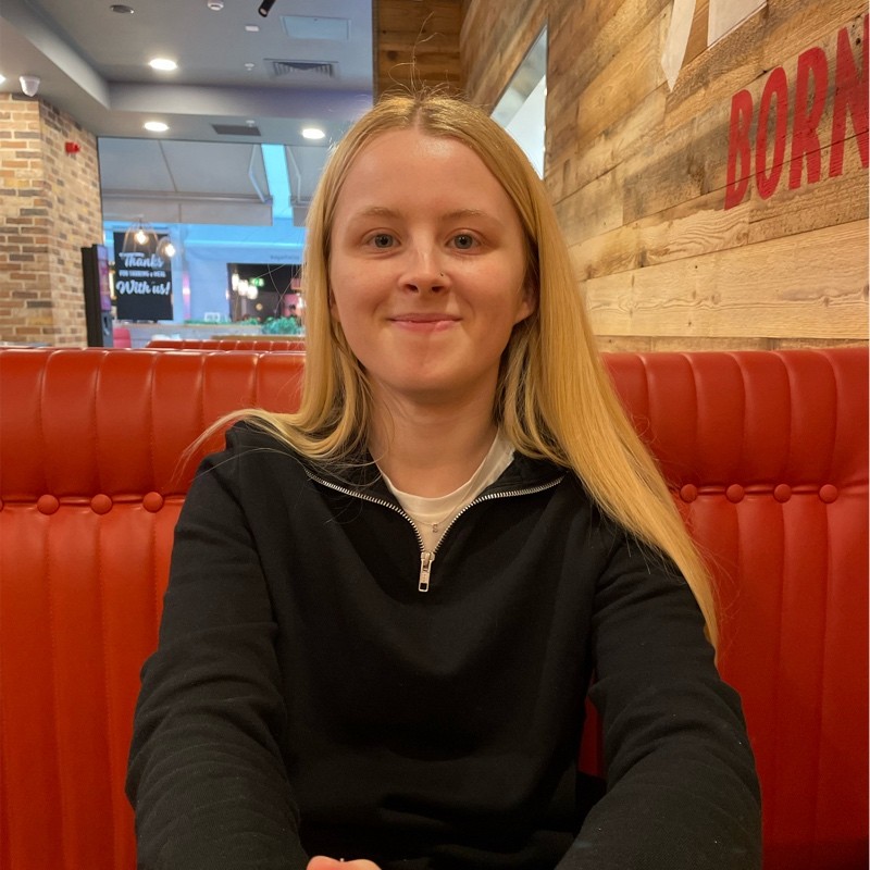 Photo of a white woman with blonde hair wearing a black jumper smiling