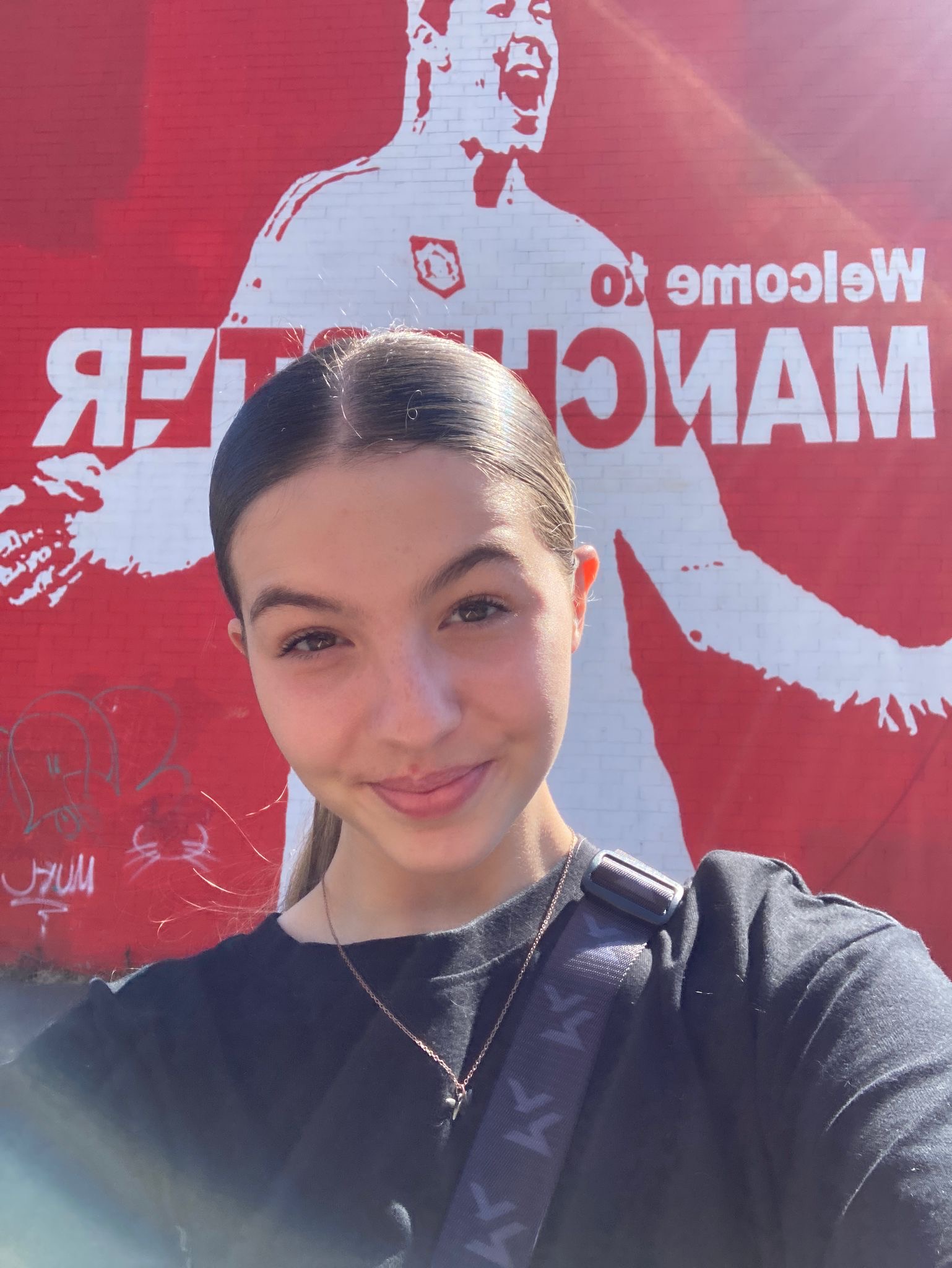 Selfie of a white woman with dark brown hair in a slick back ponytail