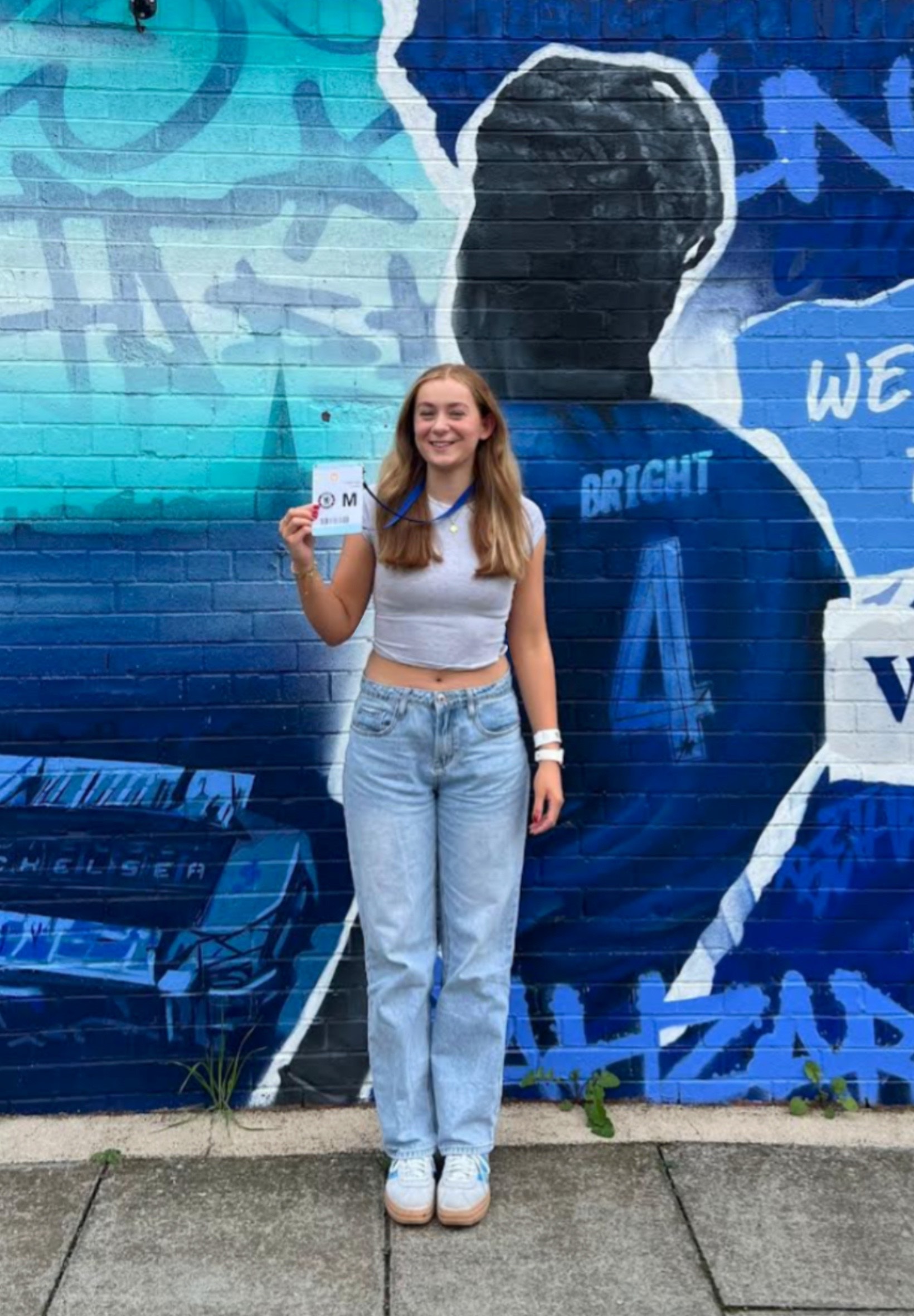 Photo of a white woman with ginger hair holding a press pass in her hand