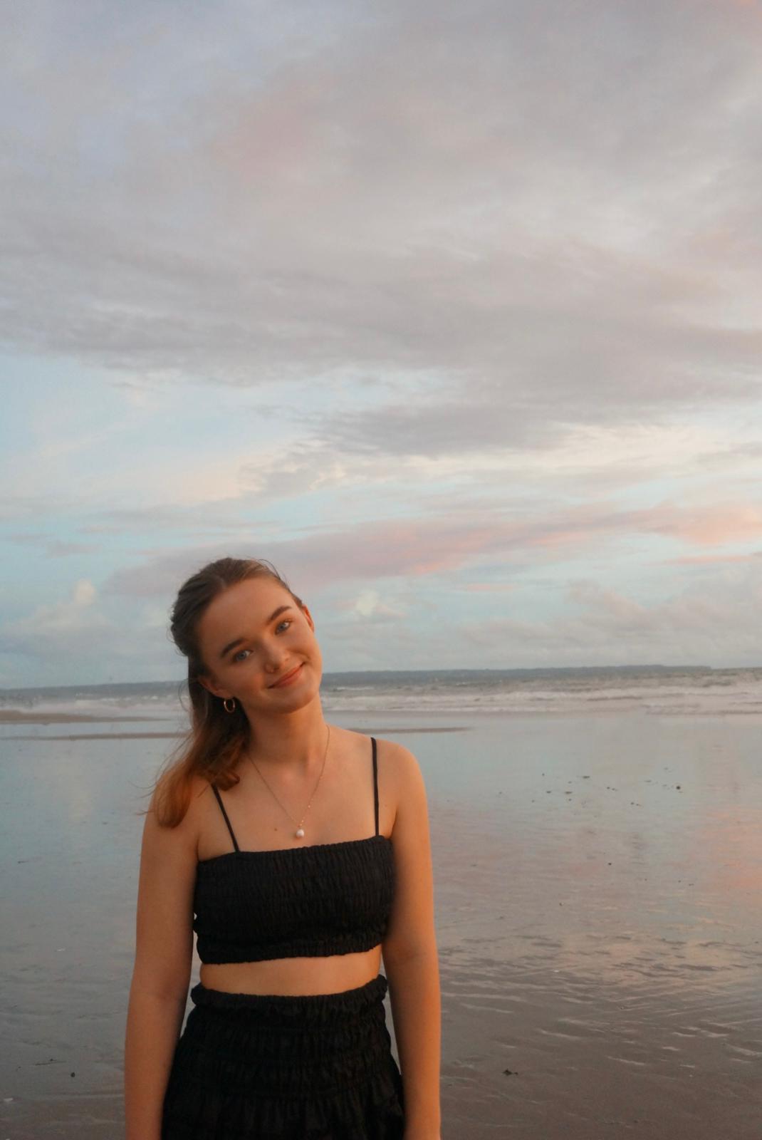 Photo of a white woman wearing a black top at the beach