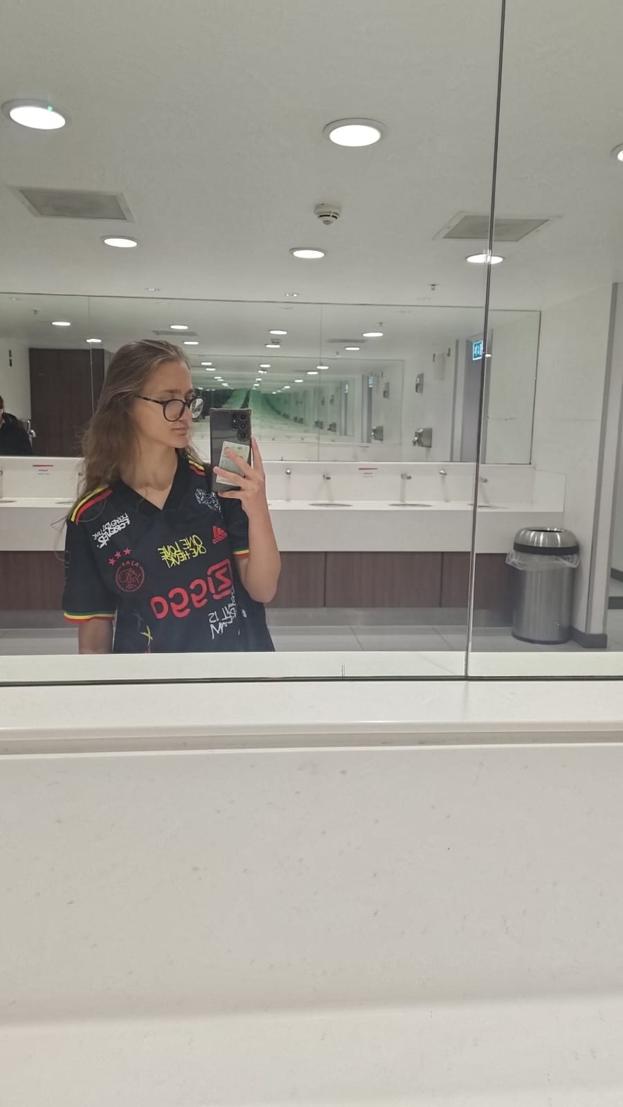 Mirror selfie of a white woman with light brown hair with black glasses