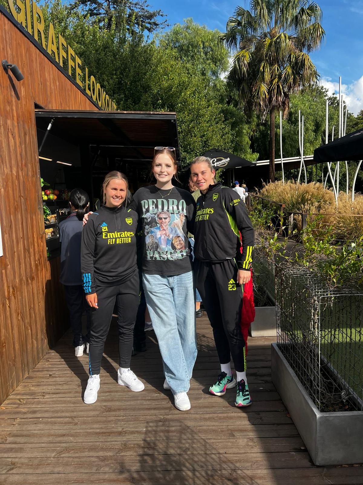 Photo of a tall white woman with red hair standing between football players Alessia Russo and Victoria Pelova