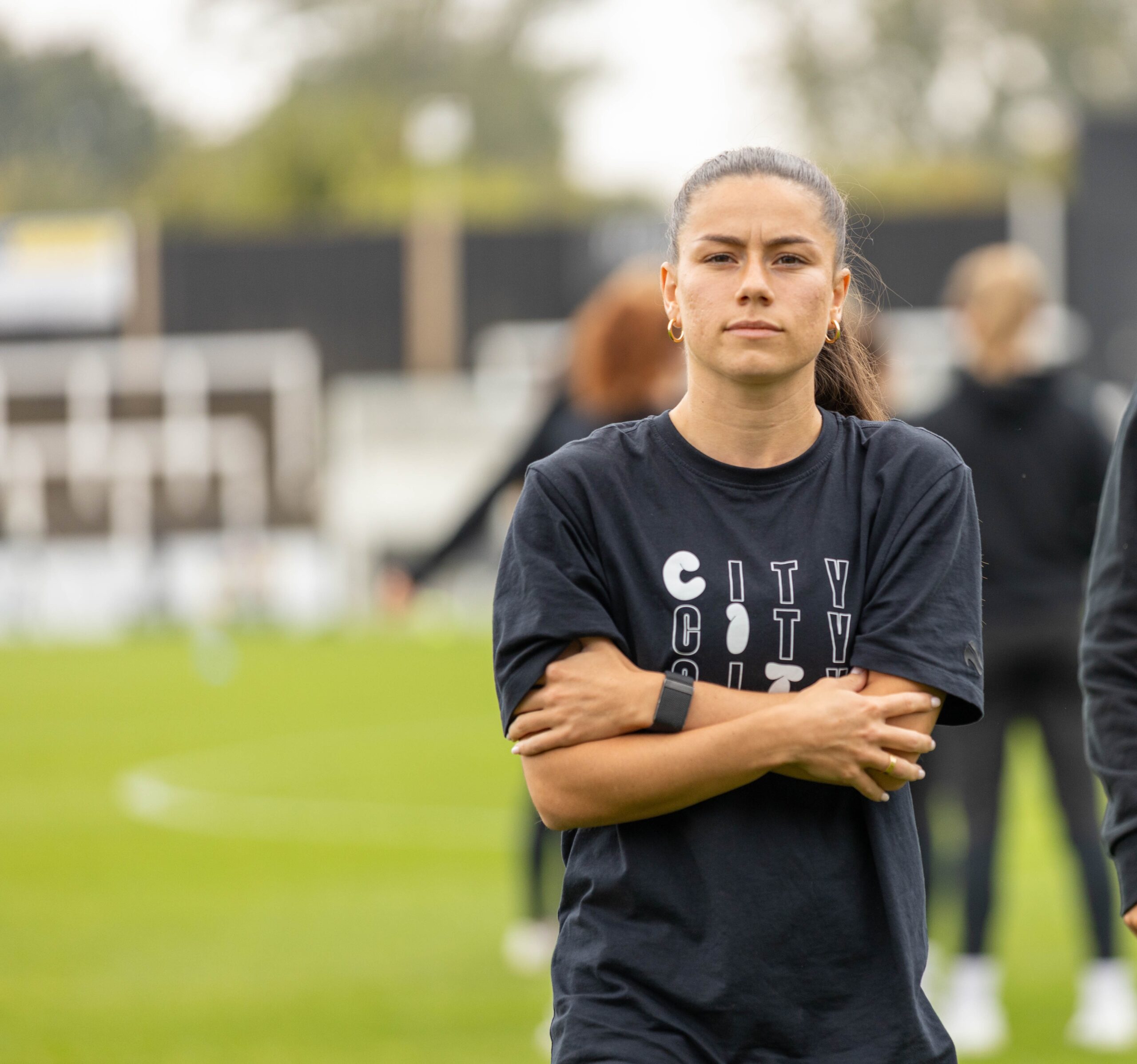 Ffion Morgan standing with her arms crossed on a football pitch.