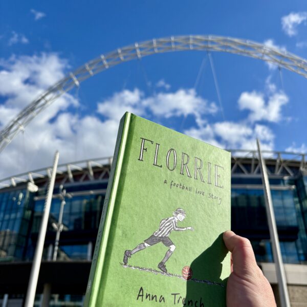 Green book held in front of Wembley Stadium