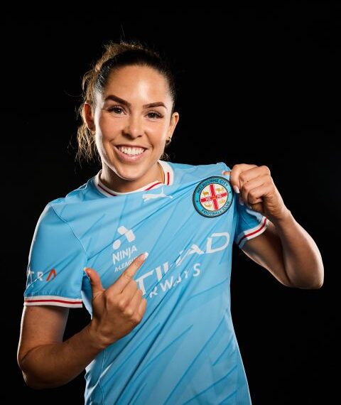 Ellie Wilson wearing a light blue Melbourne City football shirt against a black backgroud