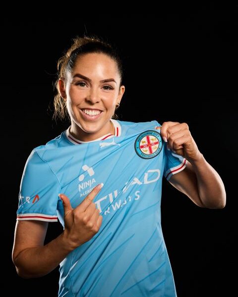 Ellie Wilson wearing a light blue Melbourne City football shirt against a black backgroud