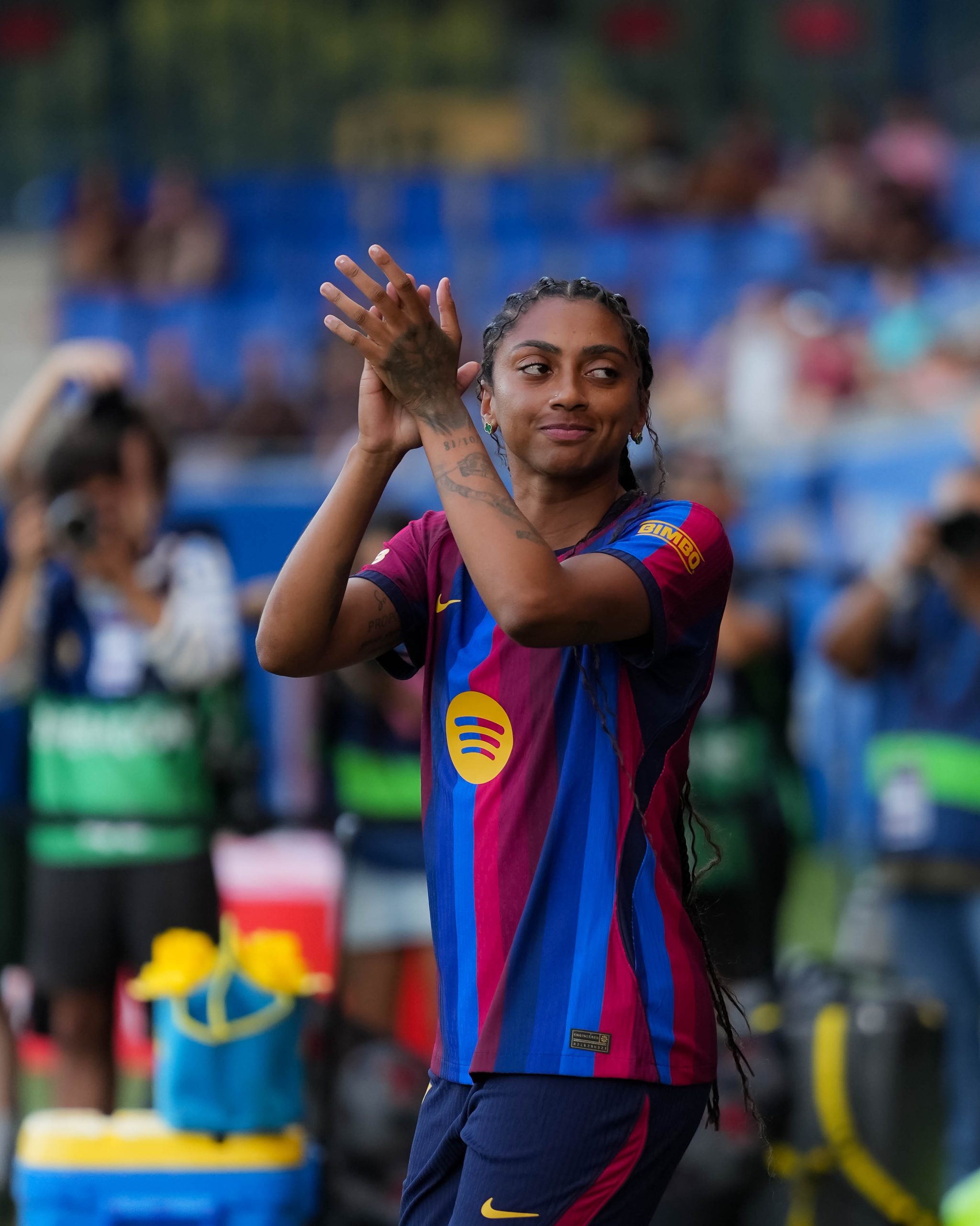 FC Barcelona forward Kerolin applauds supporters while wearing the club’s red and blue home kit on the pitch.