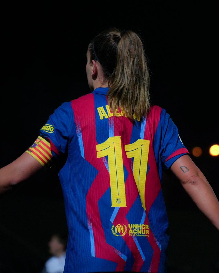 Alexia Putellas wearing Barcelona’s red and blue home shirt, pictured from behind with number 11 on the back and a captain’s armband on her left arm.