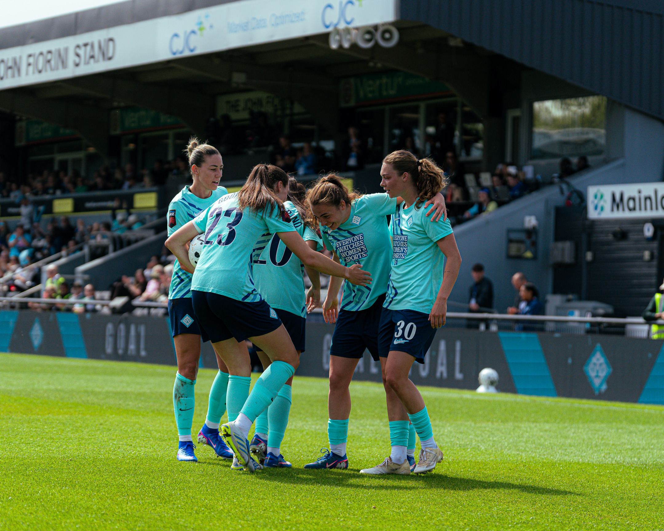 London City Lionesses players celebrate together on the pitch during a home match.
