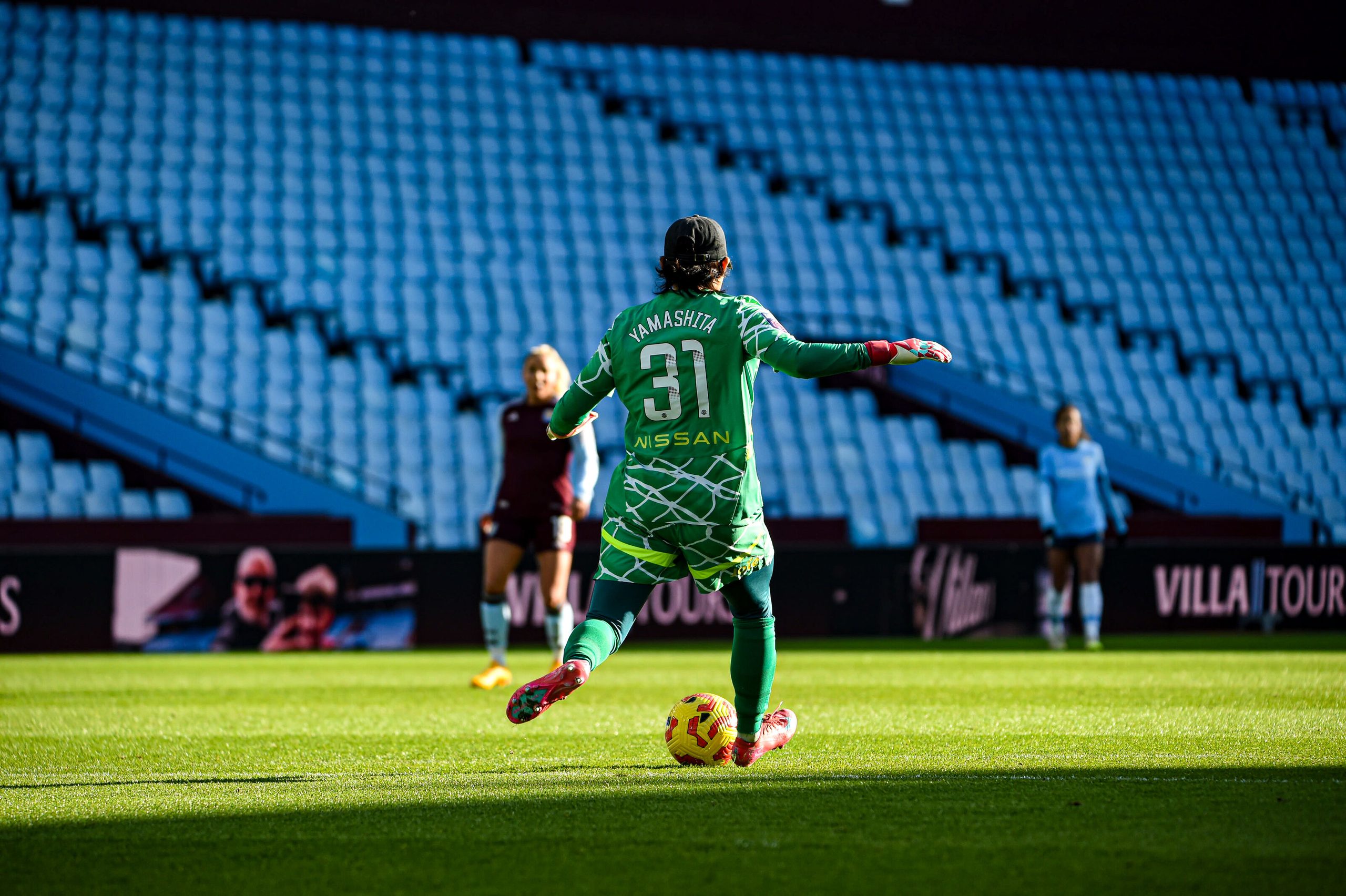 Yamashita goes to kick ball from goal kick in green Manchester City goalkeeper kit with her name and the number 31 on the back of her shirt. You can see seats on the stand of the stadium in the background.
