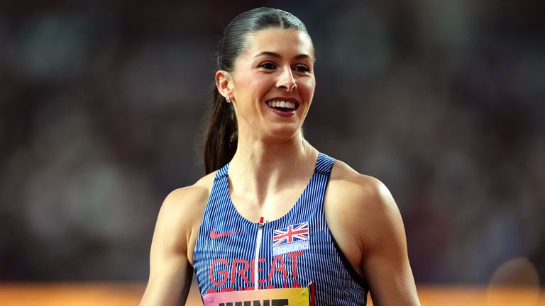 Amy Hunt wearing a blue Team GB athletics vest at a track event, with her hair tied back in a ponytail and a blurred stadium background.