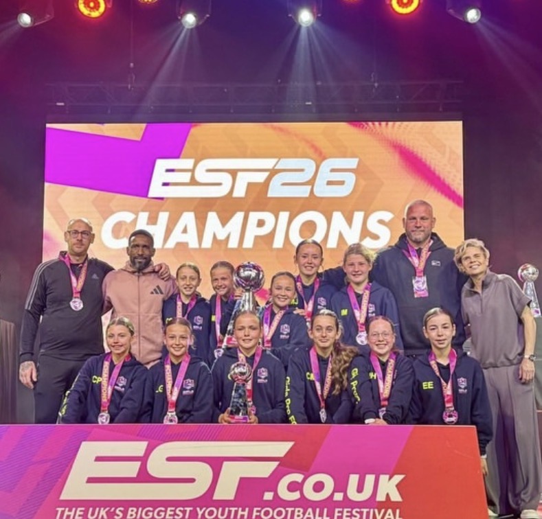 A Girlspro team at a ESF Competition holding a trophy on stage.